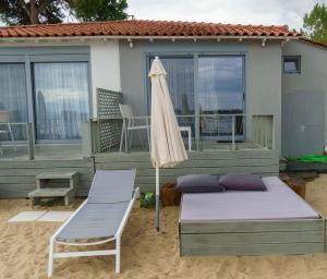 a bed and a chair and an umbrella on a deck at Zinozis Beach Apartments in Vourvourou