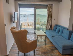 a living room with a blue couch and a view of the ocean at Zinozis Beach Apartments in Vourvourou