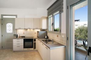 a kitchen with white cabinets and a large window at Alkmini Apartment in Loutra