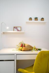a desk with a yellow chair and flowers on it at Alkmini Apartment in Loutra