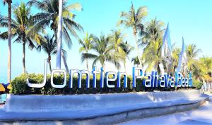 een bord bij de ingang van een resort met palmbomen bij Sea View Beachfront Condos Pattaya Jomtien Beach in Jomtien Beach