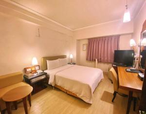 um quarto de hotel com uma cama grande e uma secretária em 種子商旅 em Kaohsiung