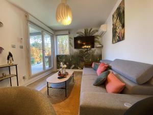 a living room with a couch and a table at Le Jungle : T2 avec jardin et jacuzzi in Blagnac