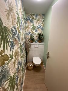 a bathroom with a toilet and plants on the wall at Le Jungle : T2 avec jardin et jacuzzi in Blagnac