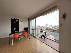 Zimmer mit einem Tisch und Stühlen sowie einem großen Fenster in der Unterkunft Le Brooklyn - T2 à Compans avec vue remarquable in Toulouse