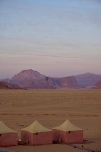 3 tende nel deserto con montagne sullo sfondo di Aljawhara camp and activities a Wadi Rum