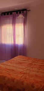 una camera con letto e finestra con tende viola di Le Acacie rooms - ex B&B a Termoli