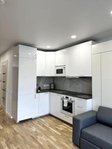 a kitchen with white cabinets and a blue couch at Wolfie Apartment, City Center in Vilnius