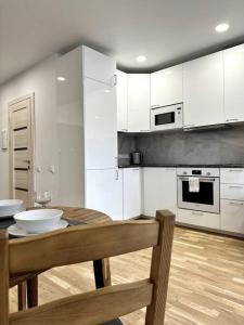 eine Küche mit weißen Schränken sowie einem Holztisch und Stühlen in der Unterkunft Wolfie Apartment, City Center in Vilnius