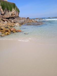 una playa con el océano y rocas en el agua en Sol de Foz en Foz