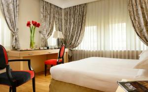 a hotel room with a bed and a desk with a desk at FH55 Grand Hotel Palatino in Rome