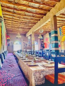 Porte De Sahara Ouzina في Ouzina: غرفة طعام كبيرة مع طاولة وكراسي طويلة