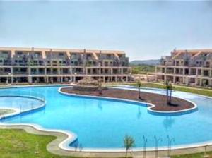 duży niebieski basen z budynkami w tle w obiekcie Cosy Apartment in Castellón with Shared Pool, 55 sqm w mieście San Rafael del Río