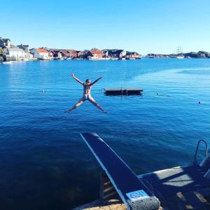 uma mulher a saltar de uma doca para um corpo de água em West coast villa with sea view em Skärhamn