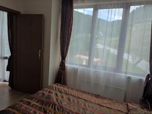 1 dormitorio con cama y ventana con vistas en Чепеларе - Пампорово апартамент на 50м от лифт Мечи Чал, en Chepelare