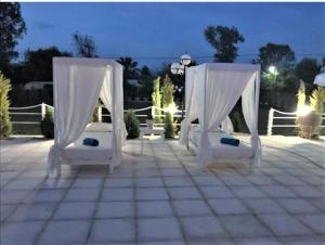 2 letti bianchi posti su un patio di notte di White Diamond Villa a Kamena Vourla