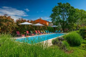 a swimming pool with lounge chairs and umbrellas at Apartmani Martina in Poreč