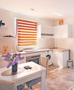 a kitchen with a table with purple flowers on it at APARTMAN OAZA in Pelinovo