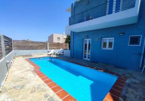 a swimming pool in front of a blue house at Ble Island in Hersonissos