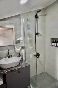 y baño con lavabo y ducha acristalada. en ReynaBe Boutique Hotel, en Dikili