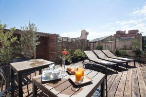 un patio al aire libre con mesas de madera, sillas y bebidas en Aspasios Urquinaona Design, en Barcelona