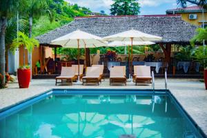 a swimming pool with chairs and umbrellas next to a house at Fleurs d'Ylang in Nosy Be