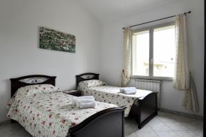 2 Einzelbetten in einem Zimmer mit Fenster in der Unterkunft casa vacanza Luciano in Tortolì