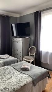 a bedroom with two beds and a dresser and a chair at Skrunda Apartments Elvira in Skrunda