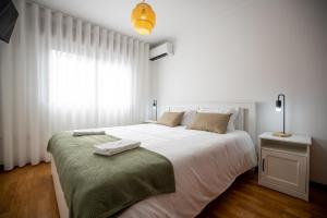 een witte slaapkamer met een groot wit bed en een raam bij Lino's Family Guesthouse in Peso da Régua