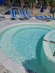 a swimming pool with blue chairs in a resort at agriturismo heaven trilocale 2 in Ricadi