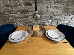 una mesa de madera con platos y copas de vino. en Apartament Jaworzno, en Jaworzno