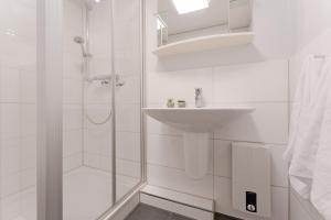 y baño blanco con lavabo y ducha. en Haus am Kurpark Scharbeutz Wohnung 2, en Scharbeutz