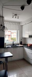a kitchen with white cabinets and a large window at Apartament Rodzinny Przy AquaParku in Reda