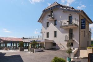 een groot wit gebouw met een parkeerplaats bij La Villa du Lac in Aiguebelette-le-Lac