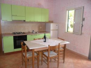 una cocina con armarios verdes y una mesa con sillas en agriturismo heaven trilocale 3, en Ricadi 9 fotos más