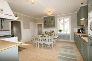 een keuken met groene kasten en een tafel en stoelen bij Spacious house in Hjo by Vattern with fantastic views in Tidaholm
