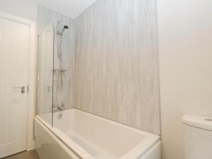 a white bathroom with a tub and a toilet at The Old School in Cinderford +21 photos
