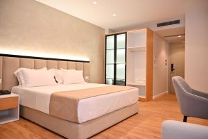 um quarto com uma cama grande e uma cadeira em Hotel Zanzi em Durrës