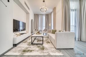 a living room with a white couch and a tv at Refined 2BR with Assistant Room at Mesk 1 Midtown Dubai Production City by Deluxe Holiday Homes in Dubai