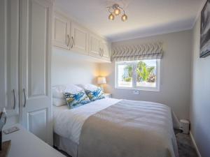 a white bedroom with a bed and a window at E19 The Warren in Pwllheli +14 photos