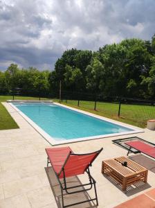 a swimming pool with two chairs and a table at Le Domaine De Dolly in Villeneuve-sur-Lot