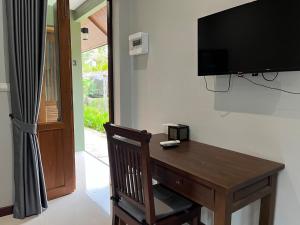 Habitación con mesa de madera y TV en la pared. en Look at Home Lamphun, en Lamphun