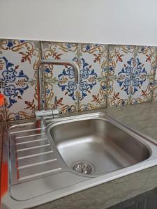 un fregadero de acero inoxidable en una cocina con azulejos en Soffio di Mediterraneo appartamento, en Trapani
