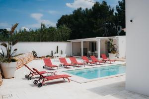 a group of red chairs sitting next to a swimming pool at Le canne Pool and Relax in Pulsano