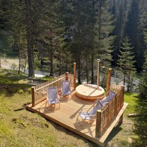 um deque de madeira com 2 cadeiras e uma banheira de hidromassagem em Vila Triglav on Pokljuka em Goreljek
