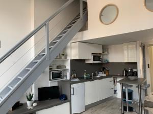 una cocina con armarios blancos y una escalera en La loge des Salinières en Burdeos