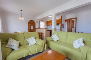 Una sala de estar con dos sofás verdes y una cocina. en Villa Loes, en Son Bou