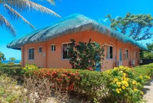 a small orange house with a thatched roof at Sunset Beach and Family Resort Gonzaga Cagayan in Bawa