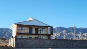 uma casa numa parede com montanhas ao fundo em Salute guest house em Kaji-Say