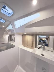 a white bathroom with a sink and a mirror at Hausboot Segelyacht Nui in Burgtiefe auf Fehmarn 